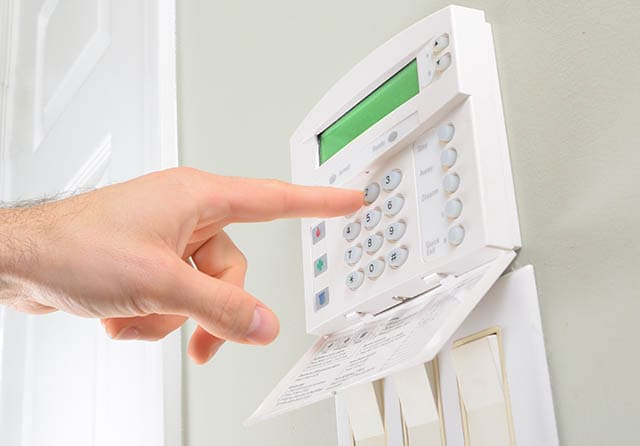 Panel de control de alarma de seguridad con teclado numérico instalado en una pared.