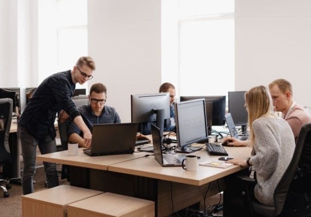 Equipo de profesionales trabajando con ordenadores y equipamiento informático en una oficina.