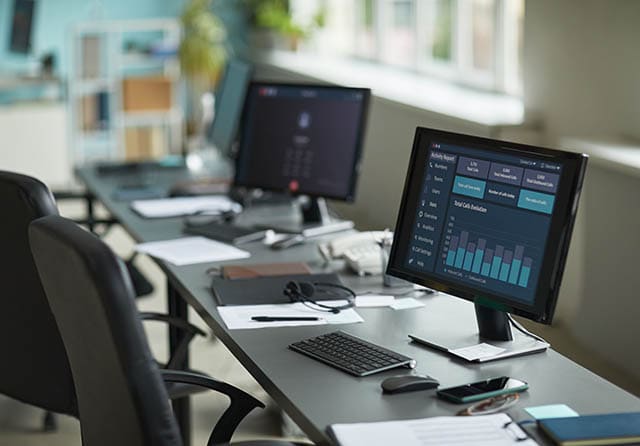 Puesto de trabajo con ordenadores, monitores y equipamiento informático de oficina.