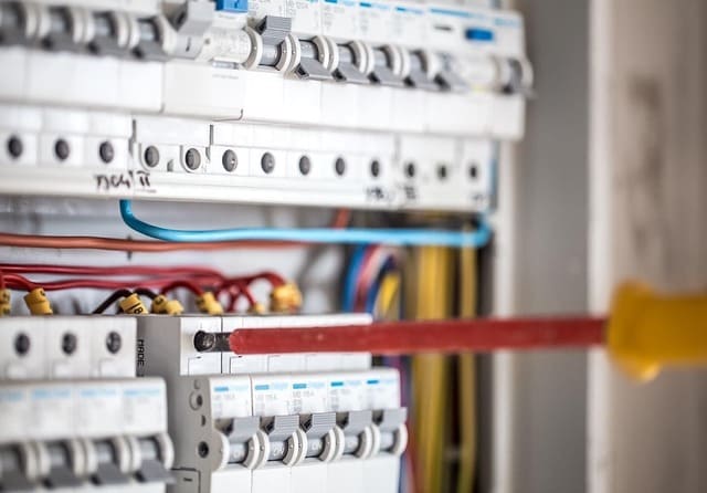Técnico realizando tareas de mantenimiento en un cuadro eléctrico con interruptores automáticos.