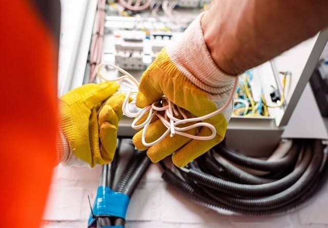 Técnico manipulando cableado durante trabajos de mantenimiento en un cuadro eléctrico.