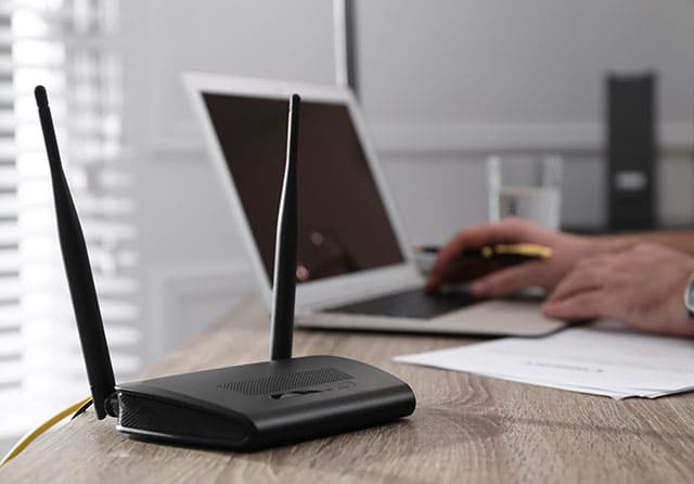 Router WiFi con antenas instalado junto a un ordenador portátil en una oficina.