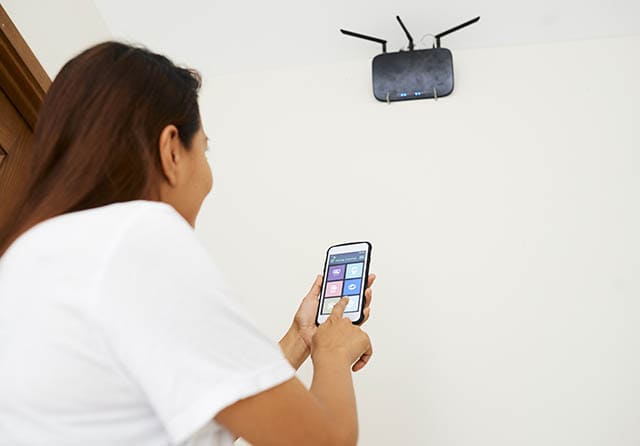 Persona utilizando un teléfono móvil conectado a una red WiFi mediante un router inalámbrico.