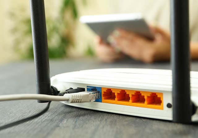 Router WiFi con cable Ethernet conectado y varios puertos de red disponibles.