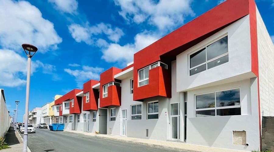 Conjunto de viviendas modernas con fachadas blancas, grises y rojas en Puerto del Rosario.